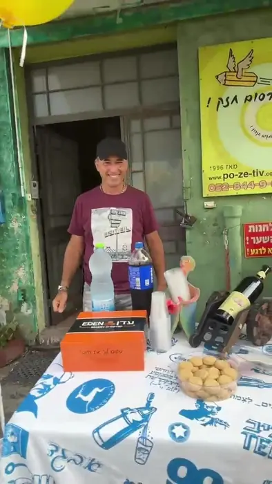 חנן אמנו מחייך מאחורי שולחן הכיבוד בחגיגת שלושים השנה של פה זה טיב באשקלון